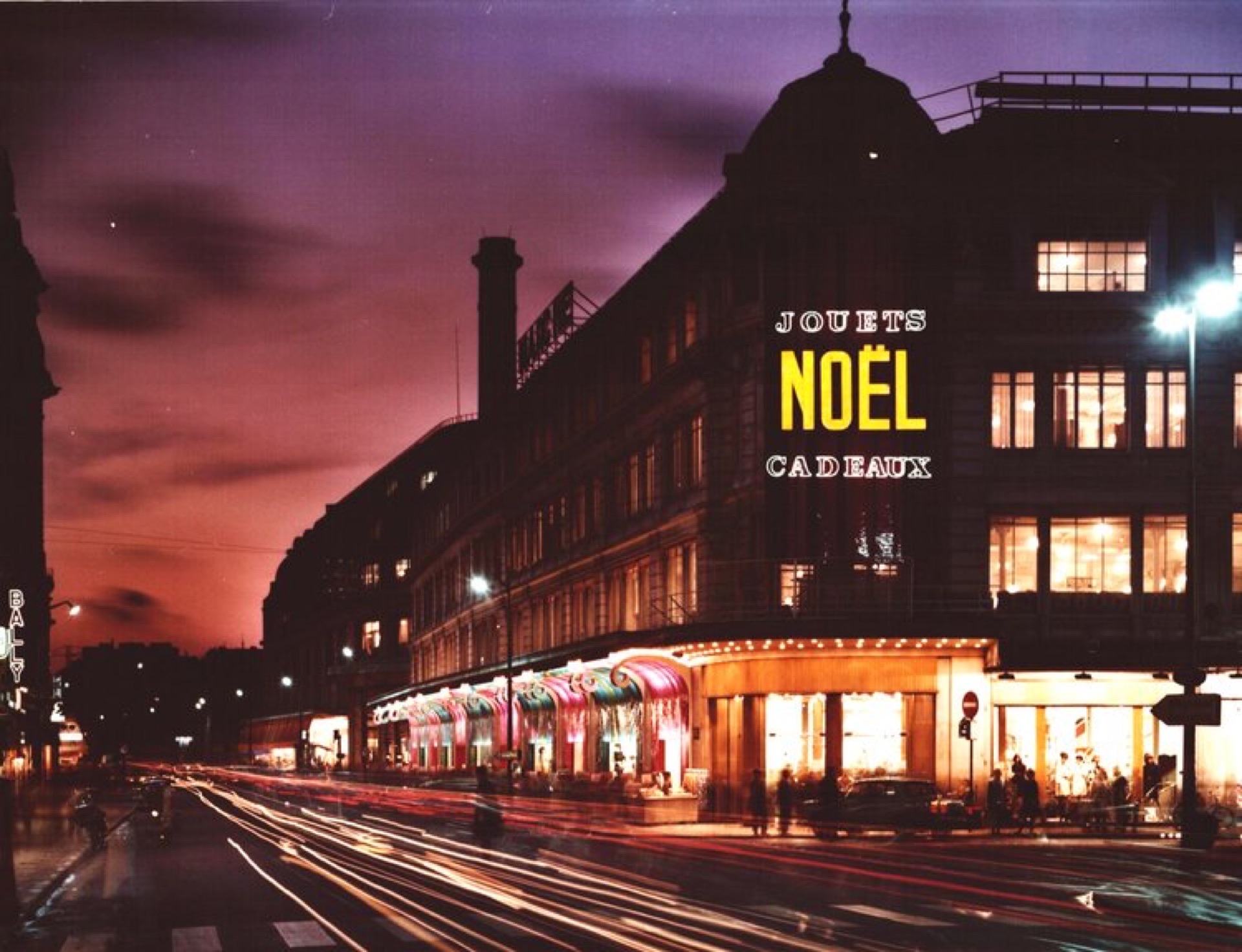Enseigne lumineuse « Jouets · Noël · Cadeaux » sur un grand magasin parisien, signée Lioté